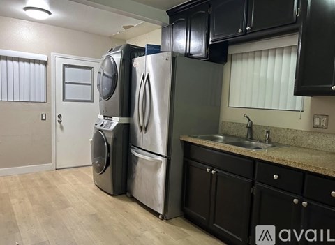 A kitchen with a stainless steel refrigerator, dishwasher, and washer.
