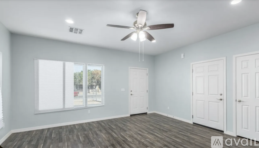 A spacious room with a ceiling fan and wooden flooring.