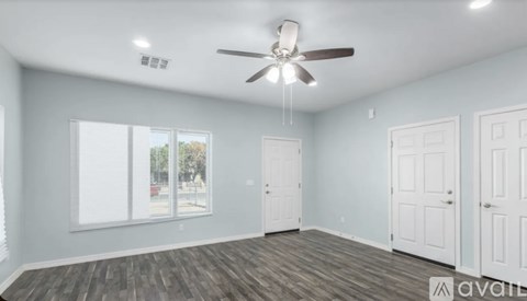 A spacious room with a ceiling fan and wooden flooring.