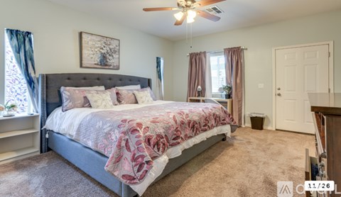 A bedroom with a large bed and a ceiling fan.