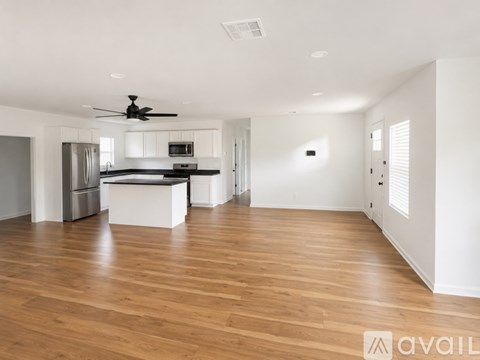 A spacious kitchen with wooden floors and a ceiling fan.