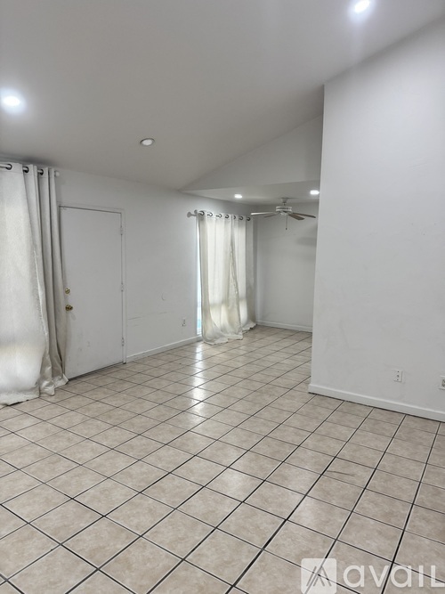 A spacious room with a tiled floor and a sliding glass door.