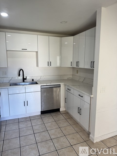 A kitchen with white cabinets and a stainless steel dishwasher.