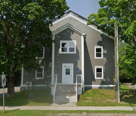 A grey house with a white door and windows.