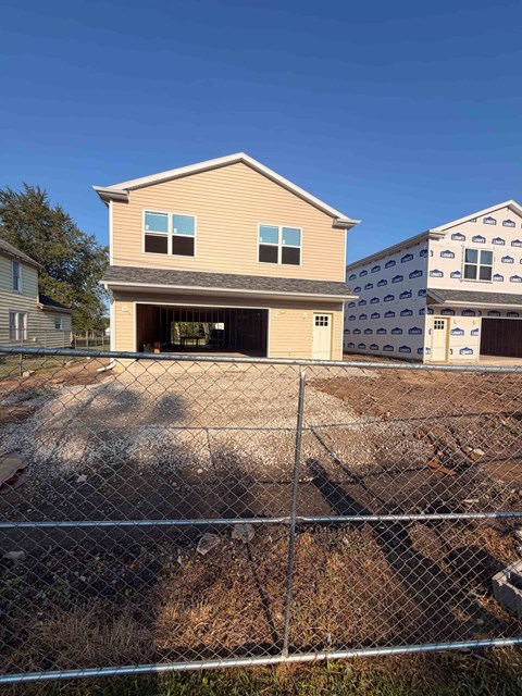 A house with a garage is in front of a chain link fence.