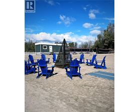 A beach scene with blue chairs and a volleyball net.