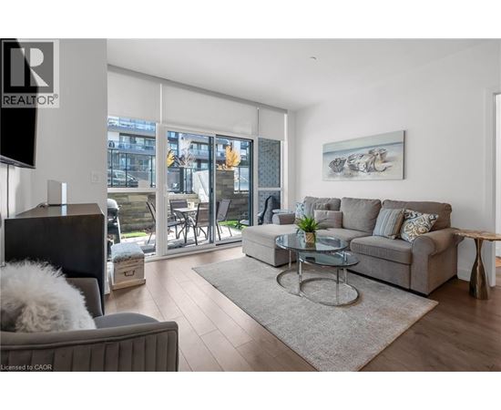 A living room with a grey couch, a glass table, and a television.