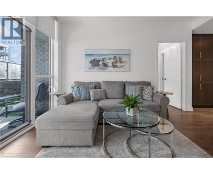 A living room with a grey couch and a glass coffee table.