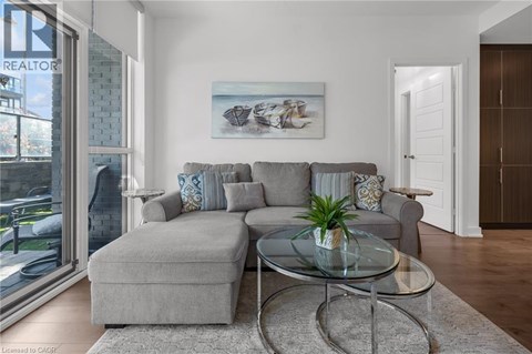 A living room with a grey couch and a glass coffee table.