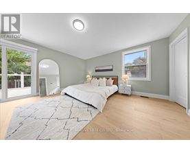 A bedroom with a large bed and a window overlooking a tree-lined street.