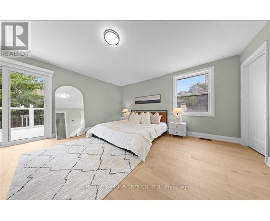 A bedroom with a large bed and a window overlooking a tree-lined street.