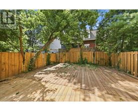 A wooden deck surrounded by a wooden fence with trees in the background.