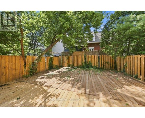 A wooden deck surrounded by a wooden fence with trees in the background.