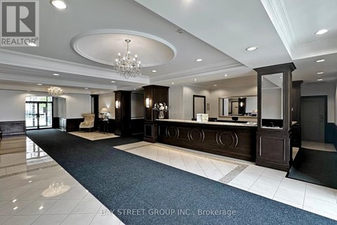 A well-lit, spacious lobby area with a reception desk and a chandelier.