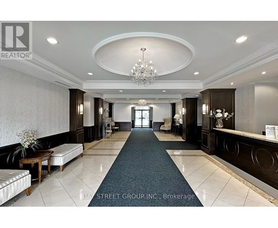 A well-lit, spacious lobby with a chandelier and a reception desk.
