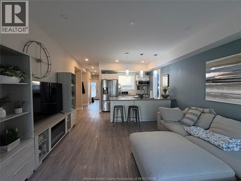 A modern living room with a grey sofa and a kitchen area in the background.