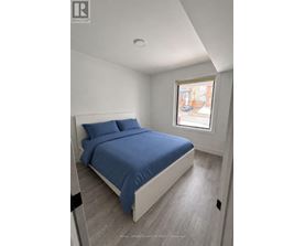 A bedroom with a bed, pillows, and a window.