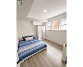 A bedroom with a bed, a nightstand, and a window.