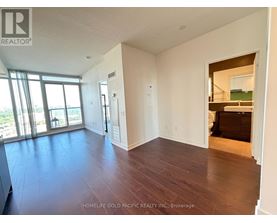 A spacious room with wooden floors and a large window.