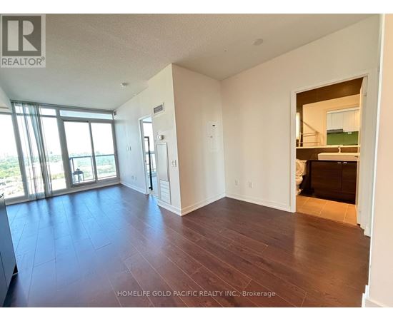 A spacious room with wooden floors and a large window.