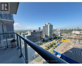 A balcony overlooks a cityscape with buildings and a parking lot.