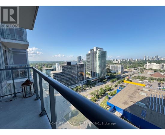 A balcony overlooks a cityscape with buildings and a parking lot.