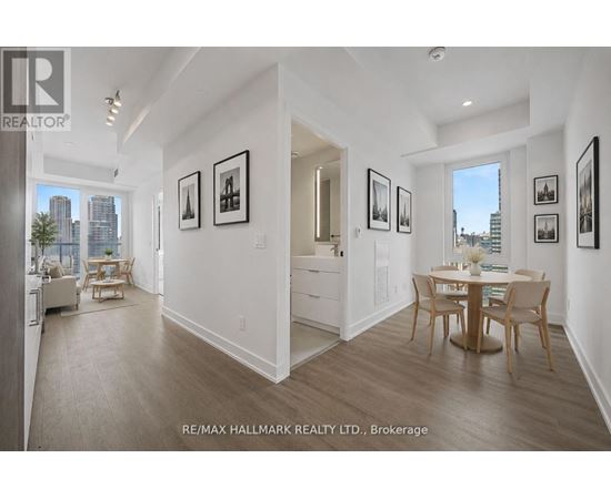 A well-lit, spacious room with a dining table and chairs, and a city view through the window.