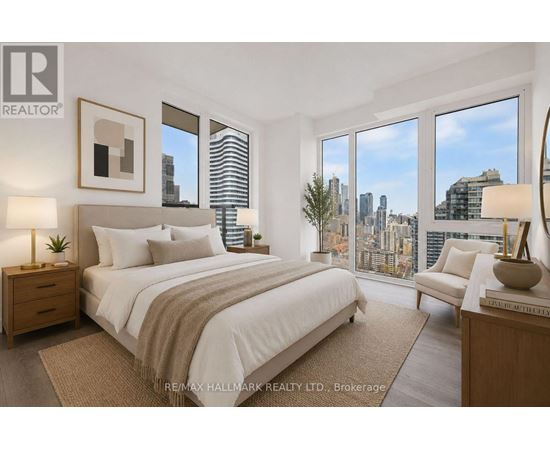 A bedroom with a large bed, a nightstand, a chair, and a view of the city.