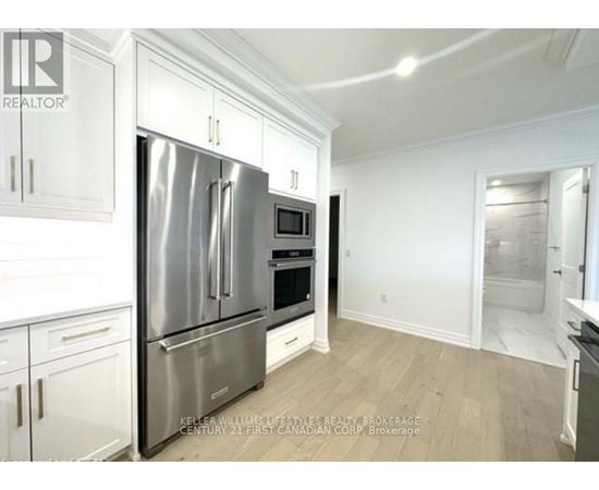 A kitchen with white cabinets and a stainless steel refrigerator.
