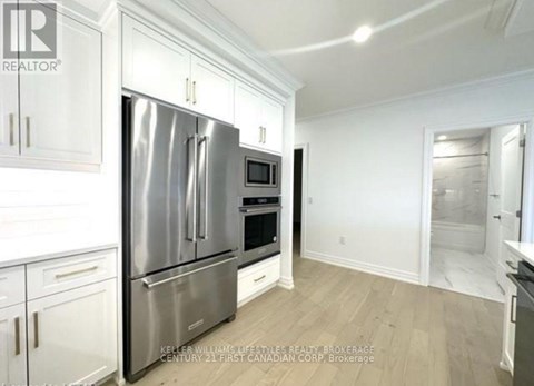 A kitchen with white cabinets and a stainless steel refrigerator.
