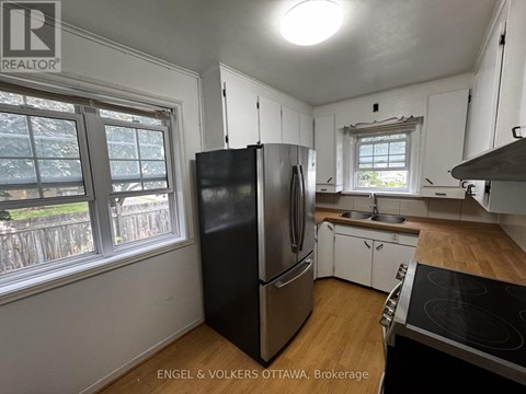 A kitchen with white cabinets and a black fridge.