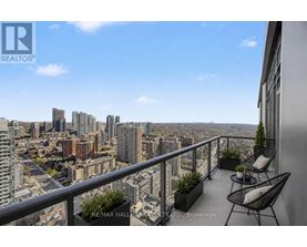 A balcony with chairs and plants overlooking a cityscape.