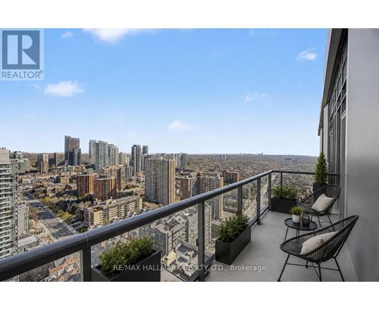 A balcony with chairs and plants overlooking a cityscape.