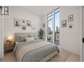 A bedroom with a large bed, a nightstand with a lamp, and pictures on the wall.