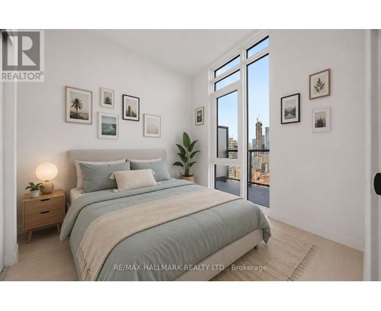 A bedroom with a large bed, a nightstand with a lamp, and pictures on the wall.