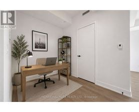 A room with a desk, chair, and a plant.