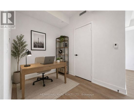A room with a desk, chair, and a plant.