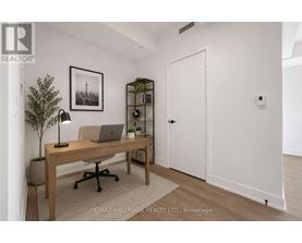 A room with a desk, chair, and a plant.