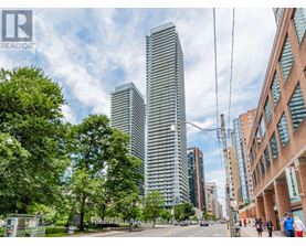 A city street with a tall building in the background and people walking on the sidewalk.