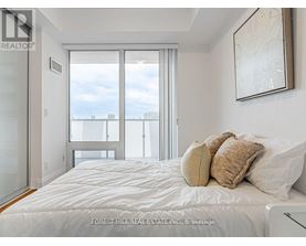 A bedroom with a large bed and a view of the city through the window.