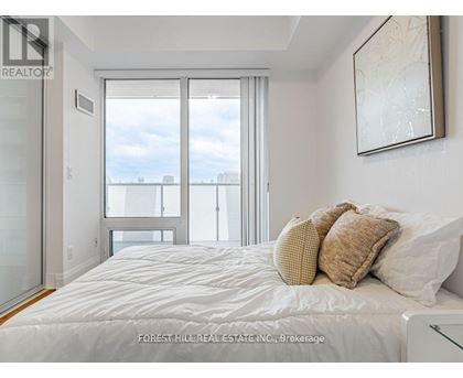 A bedroom with a large bed and a view of the city through the window.