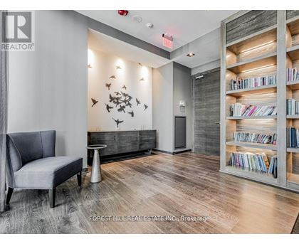 A living room with a grey chair and a bookshelf filled with books.