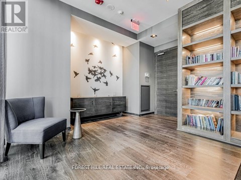 A living room with a grey chair and a bookshelf filled with books.