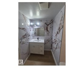 A bathroom with marble wallpaper and a white sink.