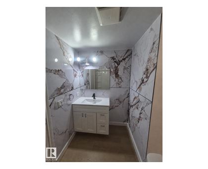 A bathroom with marble wallpaper and a white sink.