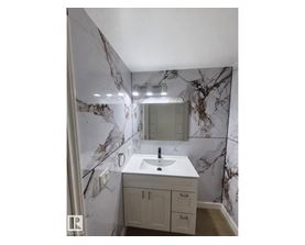 A bathroom with a marble wallpaper and a white sink.