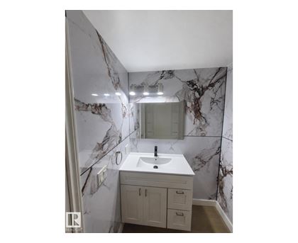 A bathroom with a marble wallpaper and a white sink.