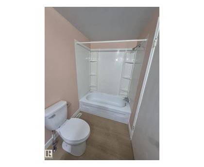 A white toilet and sink in a small bathroom.