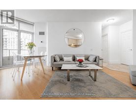 A modern living room with a grey rug, a white sofa, a wooden coffee table and a round mirror on the wall.
