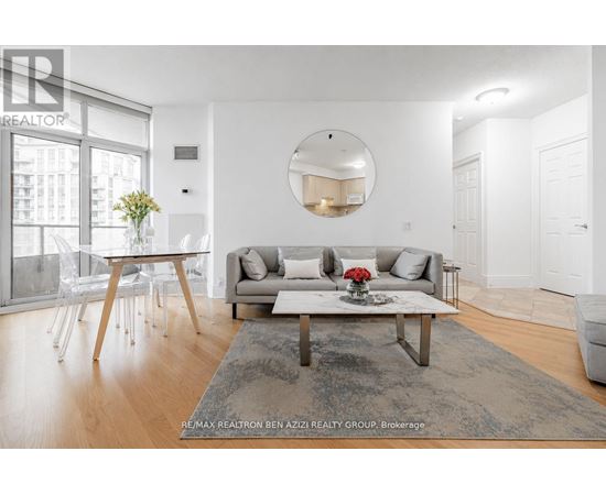 A modern living room with a grey rug, a white sofa, a wooden coffee table and a round mirror on the wall.